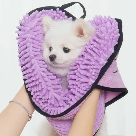 Small white dog wrapped in a purple chenille drying towel held by two hands