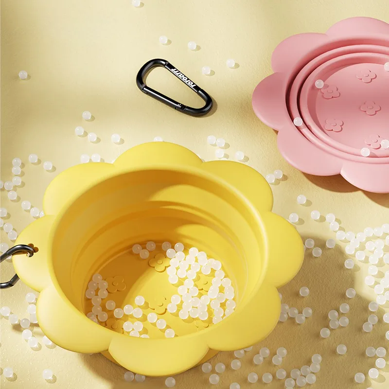 Yellow collapsible bowl opened up, with a black carabiner and the pink bowl behind