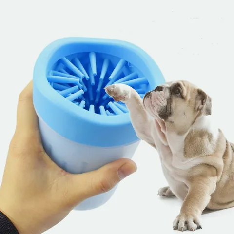 Hand holding a blue paw washer cup while a bulldog puts its paw inside